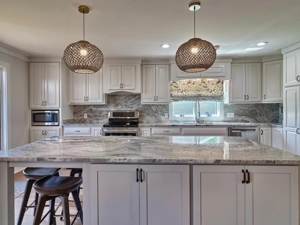 Modern kitchen with white cabinetry, marble countertops, woven pendant lights, and stainless steel appliances.