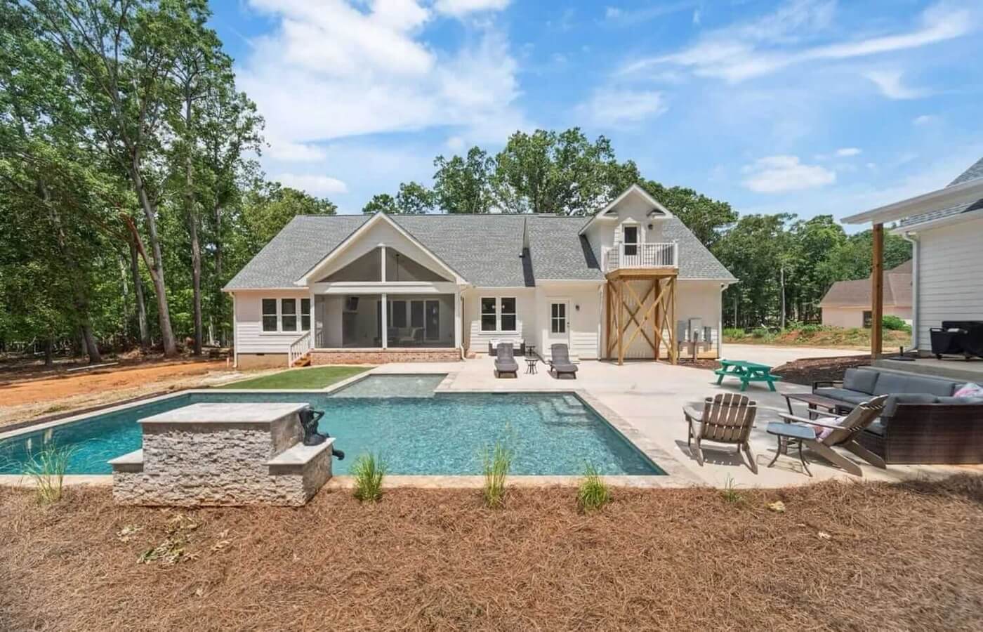 Modern home with pool, spa, and patio area surrounded by trees and landscaping