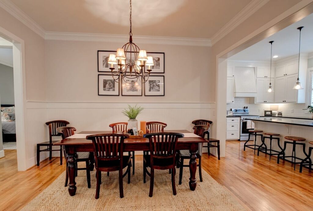 Elegant dining room with wooden table, dark chairs, chandelier, and open kitchen view.