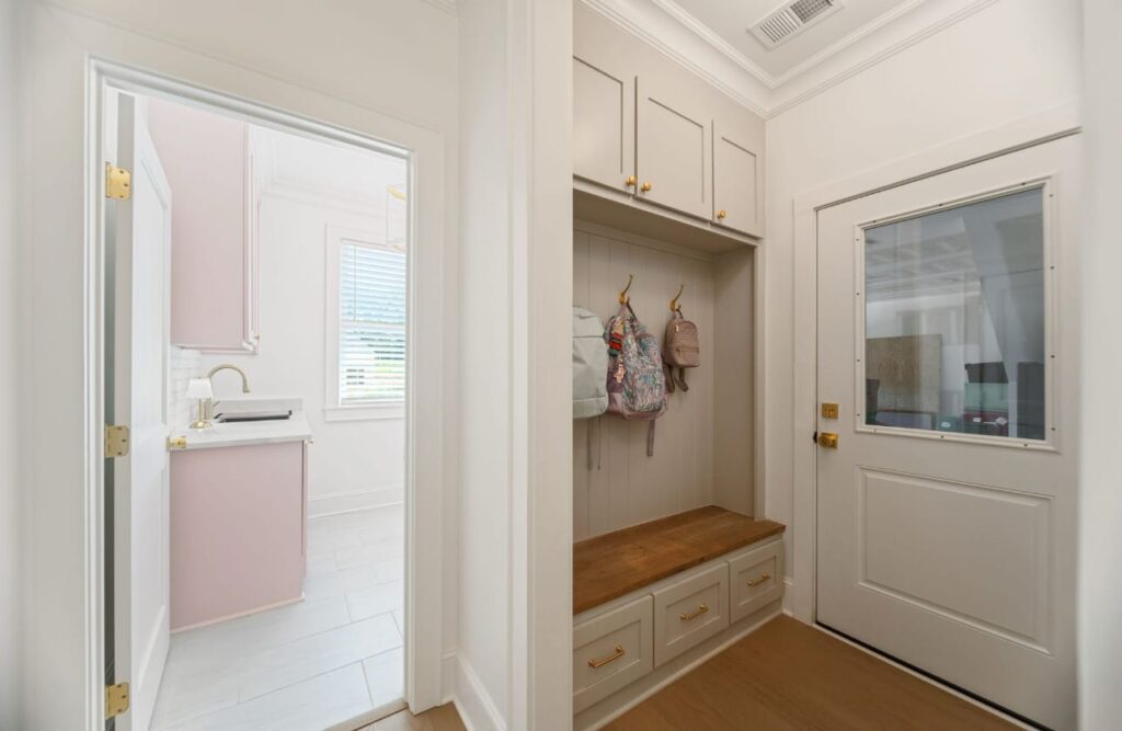 Modern mudroom with built-in bench, storage cubbies, and doors leading to bathroom and exterior