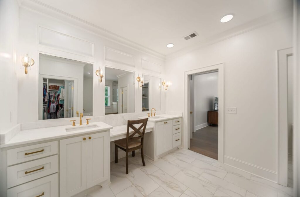 Modern luxury bathroom with white cabinetry, dual vanities, large mirrors, and marble flooring.