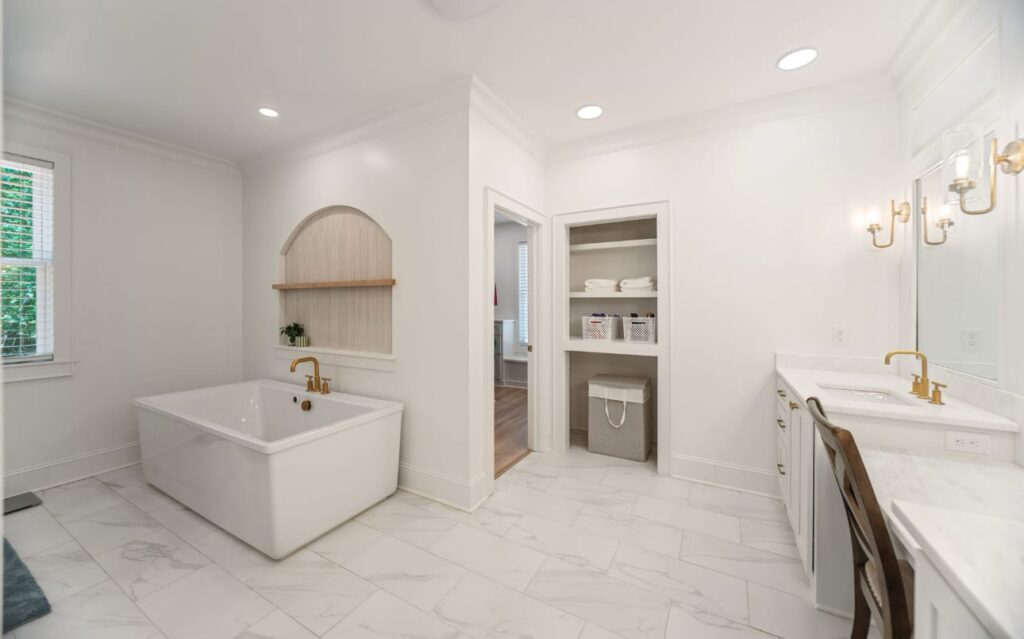 Spacious modern bathroom with freestanding soaking tub, double vanity, marble flooring, and walk-in closet.